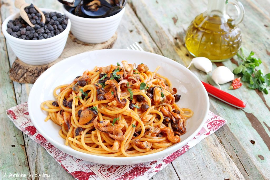 Piatto di spaghetti al pomodoro con pesce e legumi