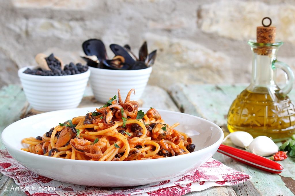 Piatto di spaghetti al pomodoro con polipetti, ceci e cozze