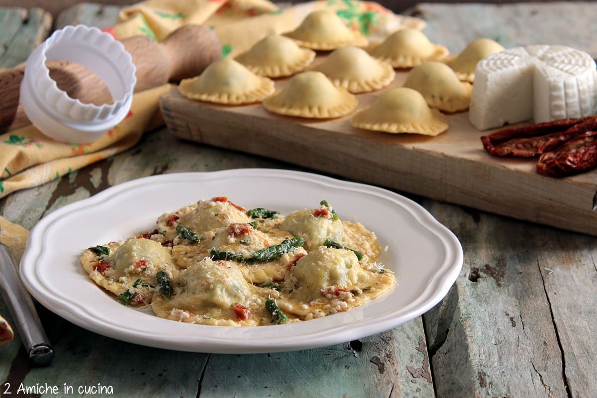 Ravioli ripieni di ricotta e asparagi conditi con ricotta, pomodori secchi e asparagi