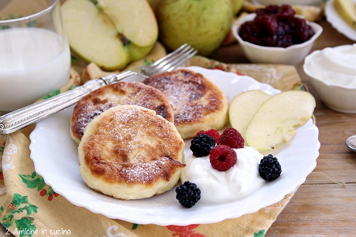 Syrniki, le frittelle russe di tvorog con mele, panna acida e frutti rossi