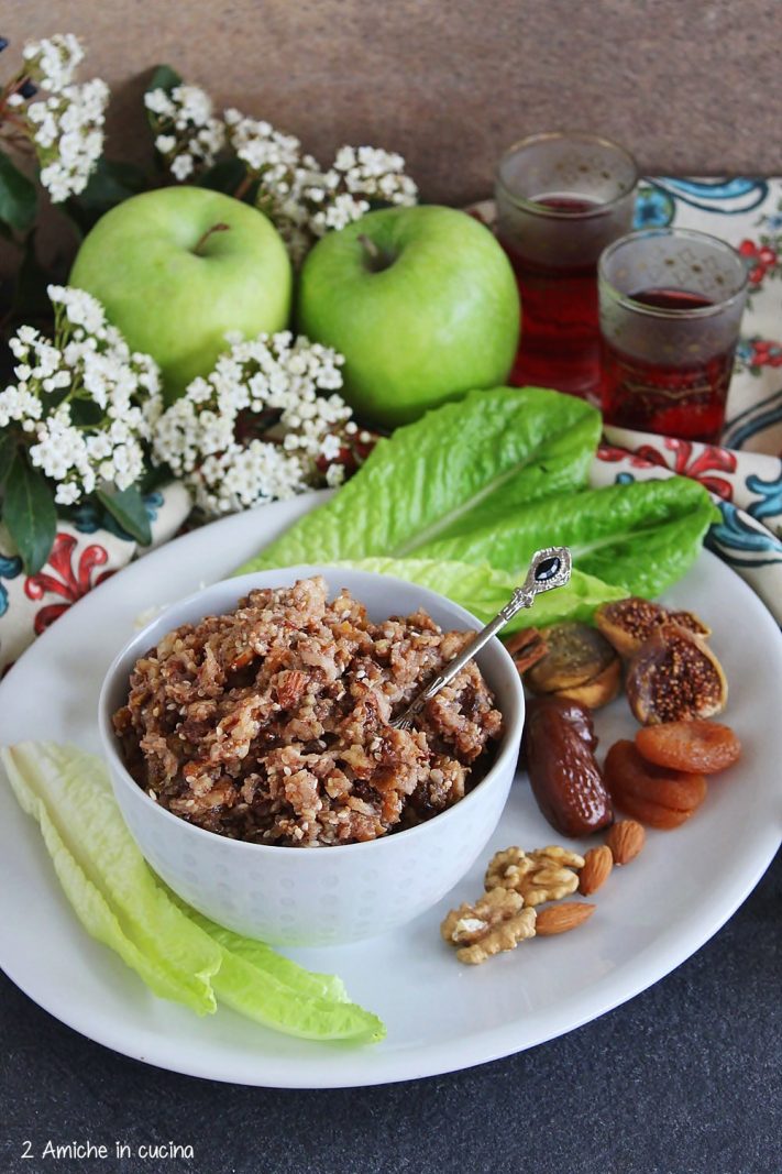 Ciotola di charoset con mele verdi e bicchierini di succo di melagrana