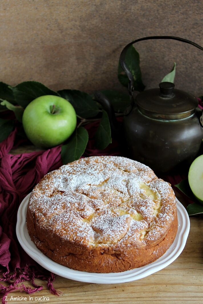 Torta di mele su piatto bianco con mela verde e teiera