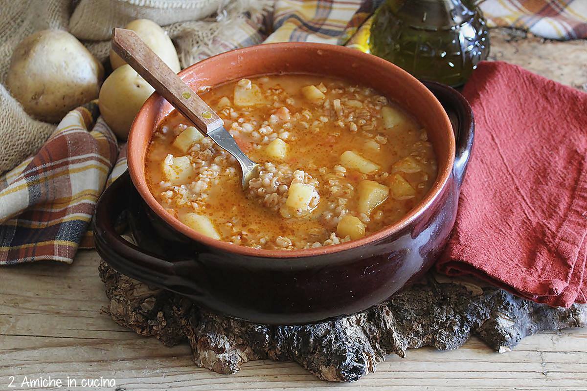 tegame di coccio con minestra e cucchiaio di legno