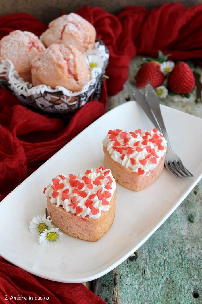 muffin rosa a forma di cuore con decorazione di panna e cuoricini di zucchero