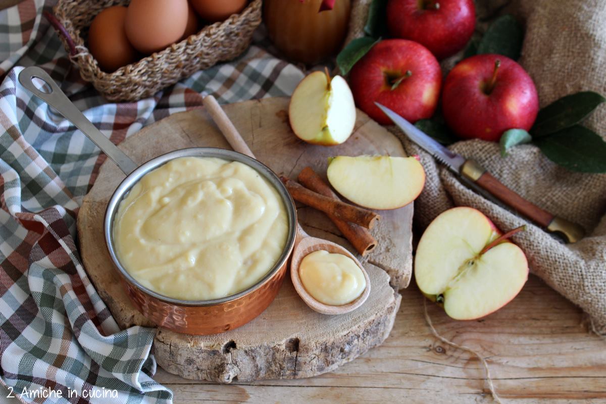 cucchiao di legno con crema alle mele, tegame in rame pieno di crema  e mele Gala